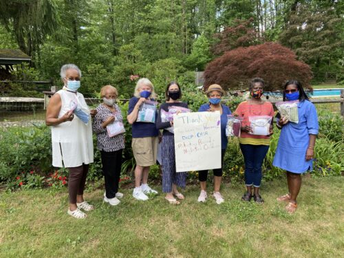 Homemade masks and sign being held by members of the Princeton Sankofa Stitchers Modern Quilt Guild and CASA staff and advisory members